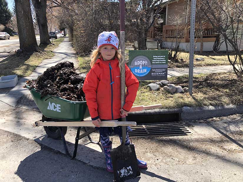 Adopt a Drain volunteer with a wheelbarrel full of debris.