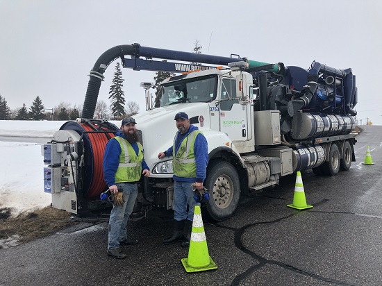 Two water/sewer operators in front of service truck