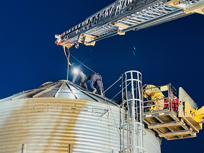 Firefighters climbing on top of a grain elevator during the evening