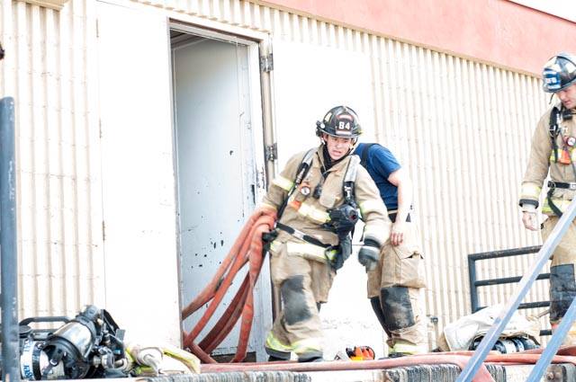 Firefighter coming out of building with hose